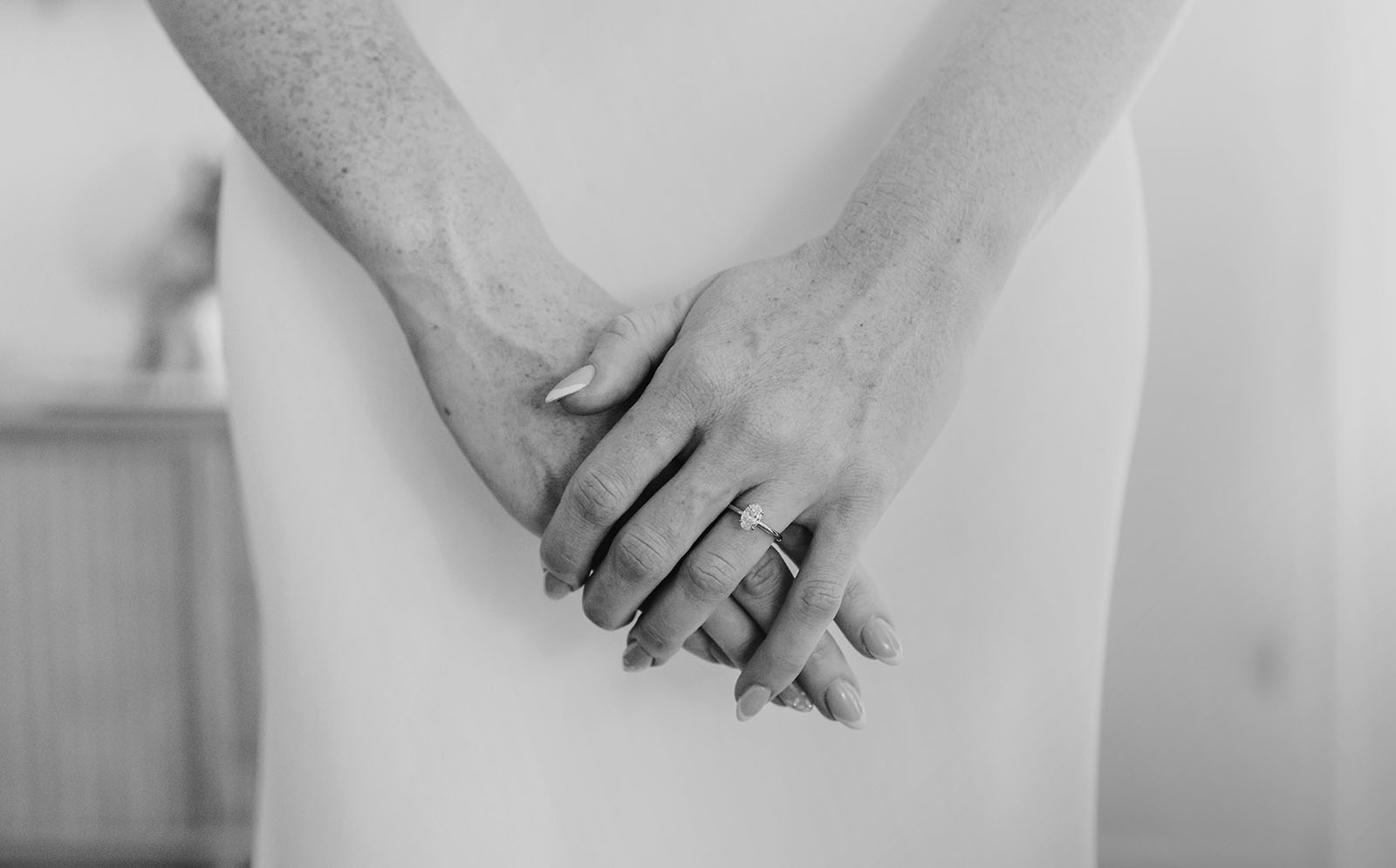 elegantly clasped hands with diamond engagement ring Elegant monochrome close-up of clasped hands showcasing a beautiful engagement ring with diamonds.